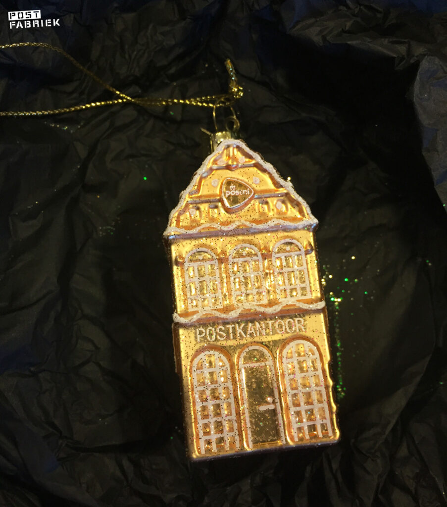 Bij twee velletjes decemberzegels krijg je een unieke kerstbal van Vondels cadeau. het is een goudkleurig postkantoortje.